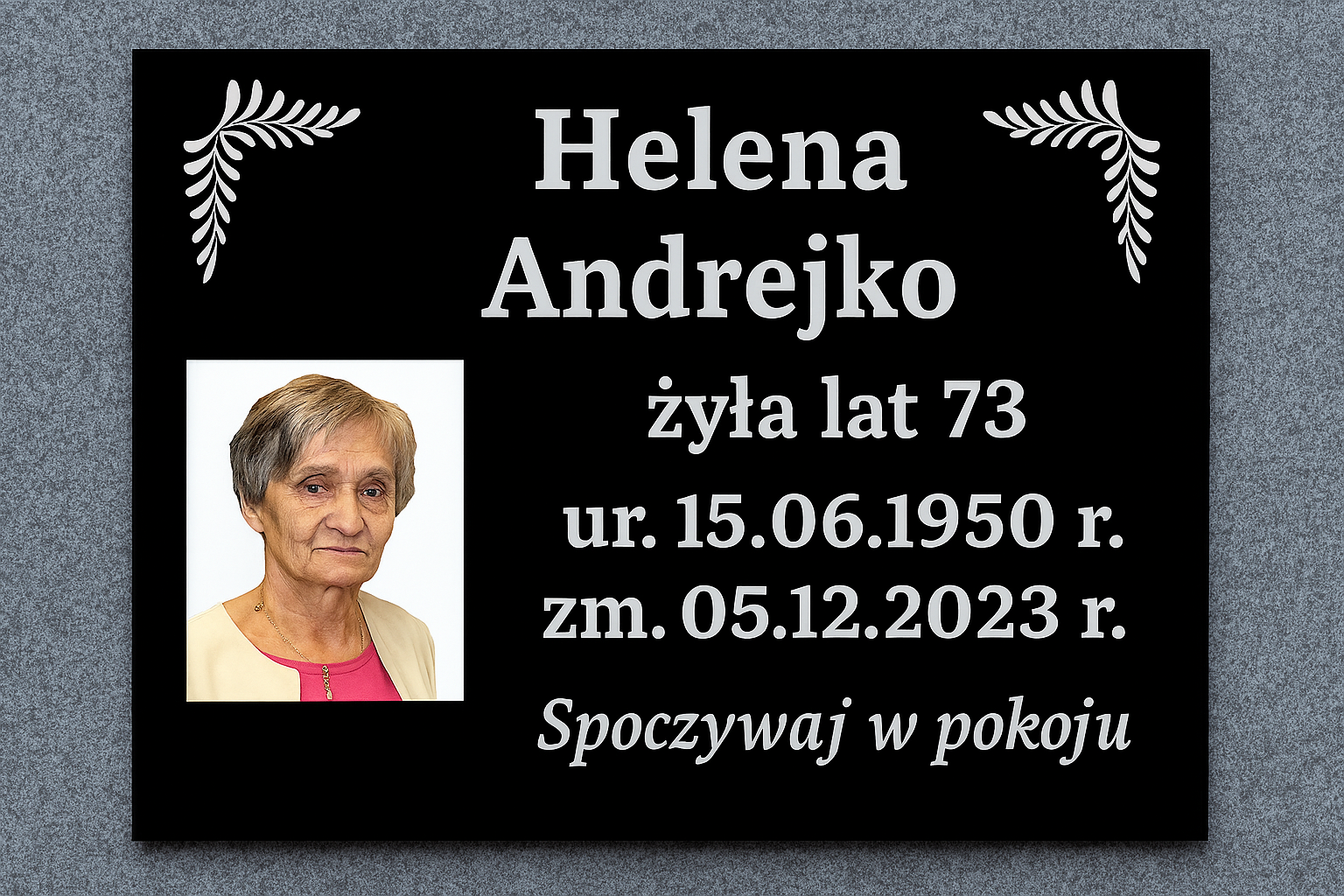 Tablica nagrobkowa z czarnej plexi z fotografią Heleny Andrejko i dekoracyjnymi motywami liści w narożnikach, z inskrypcją: żyła lat 73, ur. 15.06.1950 r., zm. 05.12.2023 r., Spoczywaj w pokoju
