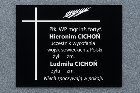 Tablica nagrobkowa z czarnego granitu z białym krzyżem i gałązką laurową, upamiętniająca Hieronima Cichonia – pułkownika WP i inżyniera fortyfikacji – oraz Ludmiłę Cichoń, z inskrypcją: Niech spoczywają w pokoju