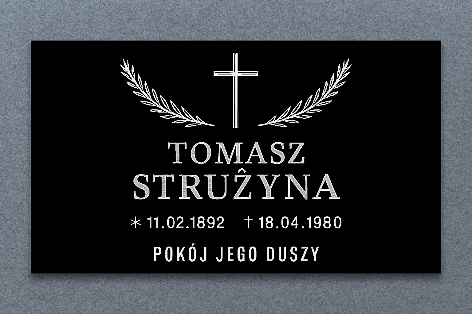 Tablica nagrobkowa z czarnej plexi z białym krzyżem i gałązkami laurowymi, upamiętniająca Tomasza Strużynę z datami życia oraz inskrypcją: Pokój jego duszy